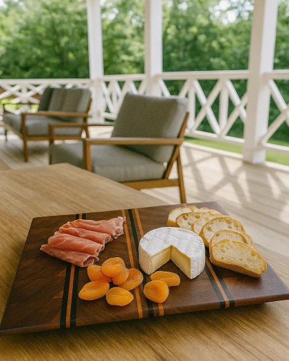 End grain Black Walnut, Cherry, and Wenge cutting board with cheese, dried apricots, and prosciutto on a patio table outdoors